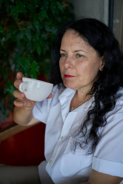 istock 60s woman drinking nettle tea in modern coworking office during lunch break 2162125144