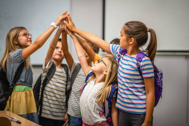 istock Group of young students give high five together in classroom 2162129050