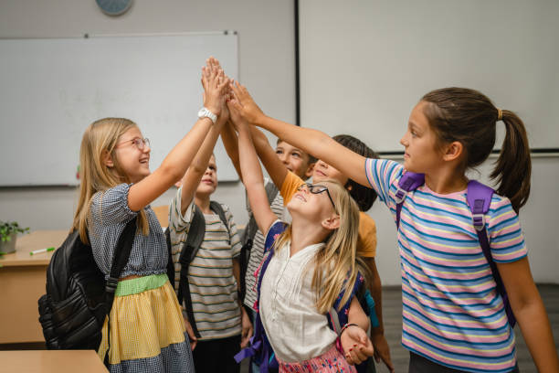 istock Group of young students give high five together in classroom 2162129093
