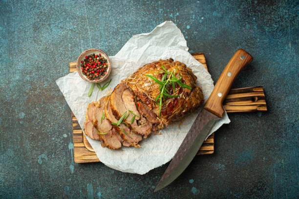 istock Rolled turkey roasted with spices and herbs on baking paper with knife and rustic concrete background top view. Baked cut for slices turkey fillet roll for dinner 2162129199