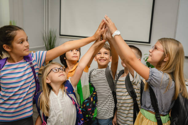 istock Group of young students give high five together in classroom 2162129329