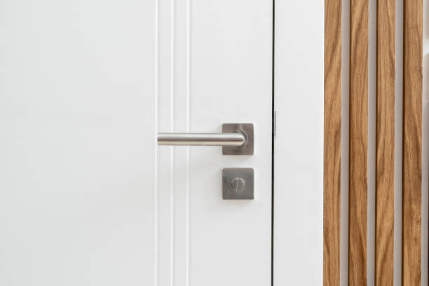 White door with silver handle and wood paneling in room