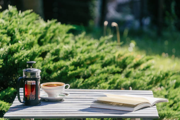 istock Coffee and book on wooden table in garden 2162129669