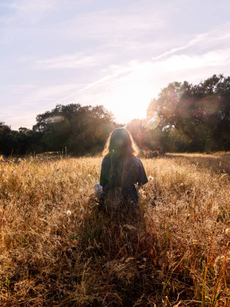 istock Girl Sitting in Sunny Meadow at Sunset 2162132005
