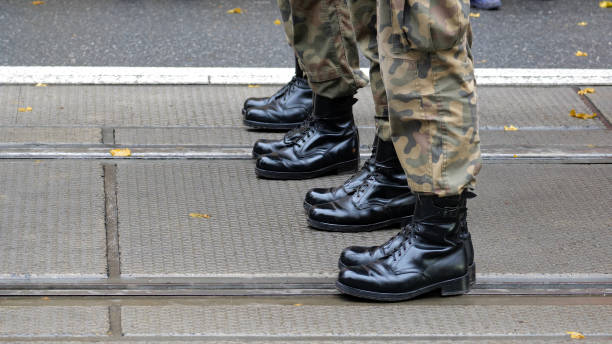 istock Anonymous unrecognizable generic infantry army soldiers standing at attention in a row on the street, legs boots closeup detail shot, copy space, green camo uniforms. Military operations border patrol 2162135961
