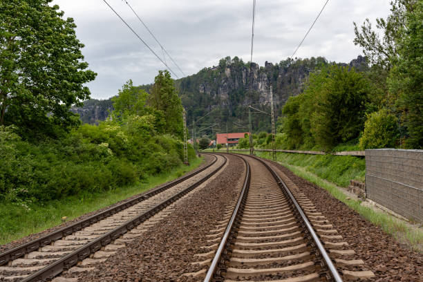 A train track with a mountain in the background. The train is not moving. The train tracks are old and worn