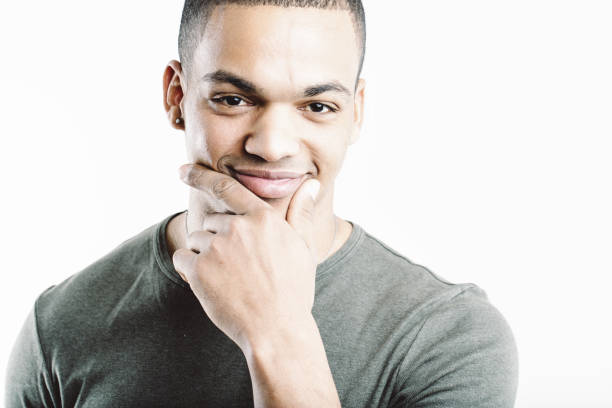 Young man in a green shirt, smiling thoughtfully with his hand on his chin. His expression and casual attire convey a sense of contemplation and confidence, suggesting he is pondering something intere
