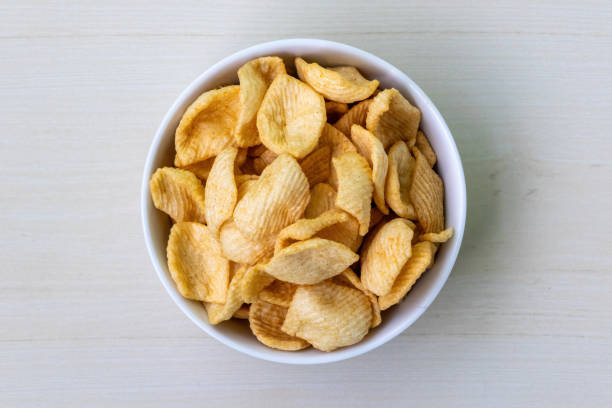 istock Potato crackers chips in a white bowl on wooden background. Top view. 2162138465