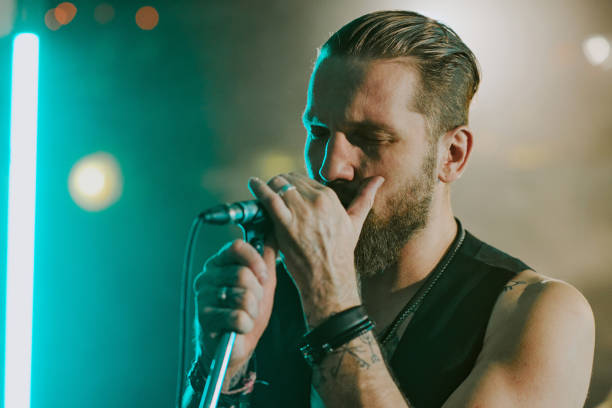 Medium closeup of Caucasian male musician singing emotional rock ballad with eyes closed on stage, copy space