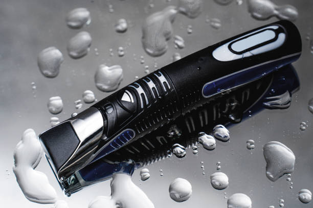 Close-up of a electric trimmer  on a reflective surface with water droplets.