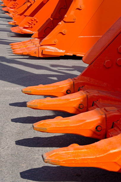 Group of orange excavator scoops, diminishing perspective shot, abstract construction industry background