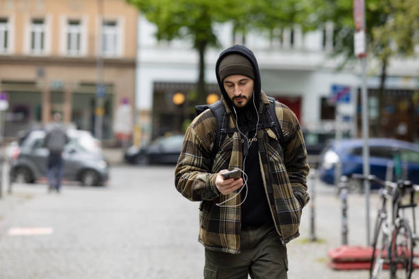 istock Young man in warm clothes walking and using mobile phone outside in city 2162141965