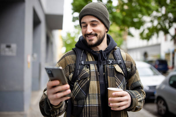 istock Handsome young man texting on his mobile phone walking outside 2162141984