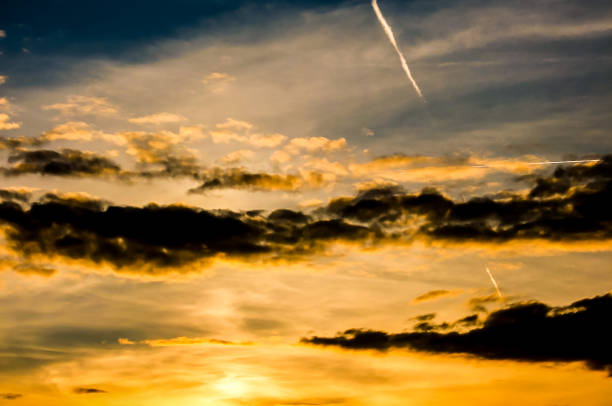 The sky is filled with clouds and the sun is setting. The clouds are orange and the sky is a mix of orange and blue