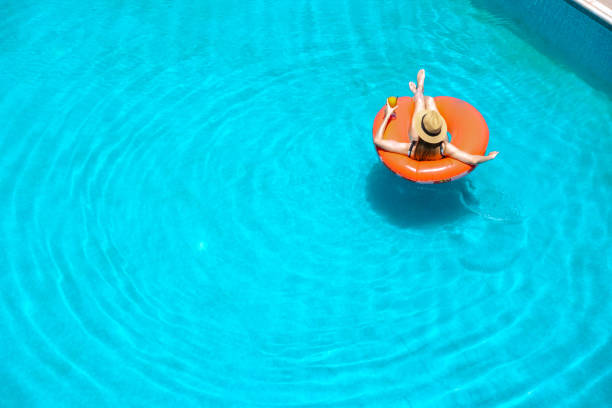 Woman relaxing on inflatable ring in swimming pool. High angle view