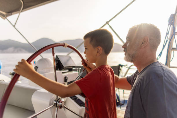 istock Father teaching his son how to steer with sailboat 2162148537