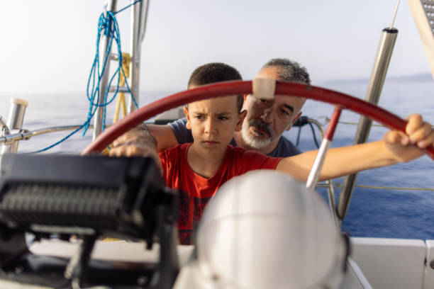 istock Father teaching his son how to steer with sailboat 2162148538