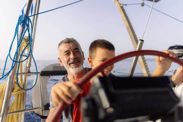 istock Father teaching his son how to steer with sailboat 2162148544