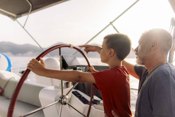 istock Father teaching his son how to steer with sailboat 2162148570