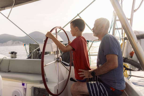 istock Father teaching his son how to steer with sailboat 2162148581