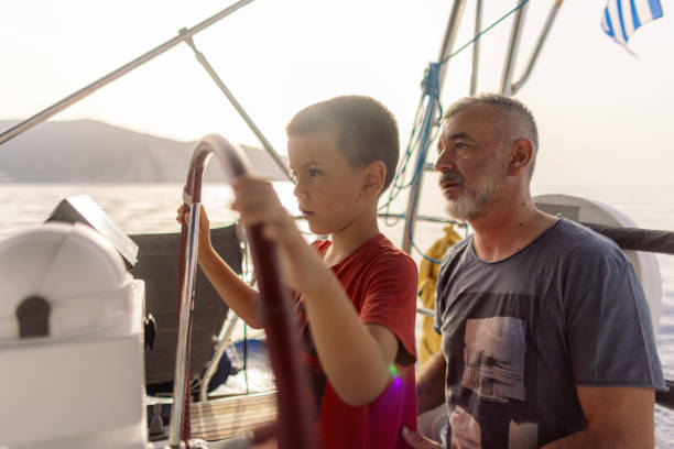 istock Father teaching his son how to steer with sailboat 2162148584