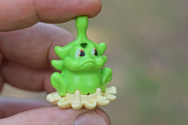 Green color clay frog holded pen on hand lying on floor with relaxation