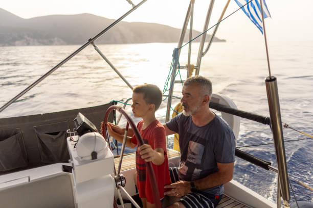istock Father teaching his son how to steer with sailboat 2162148611
