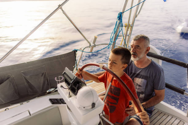 istock Father teaching his son how to steer with sailboat 2162148617
