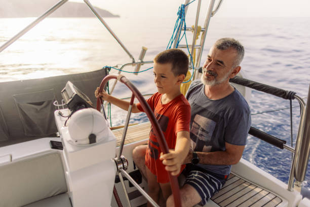 istock Father teaching his son how to steer with sailboat 2162148633