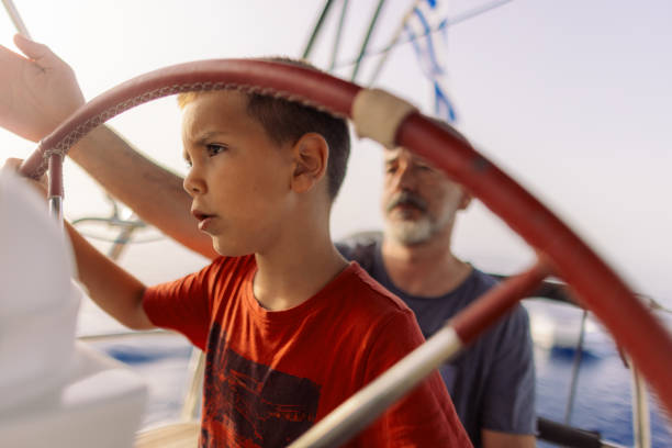 istock Father teaching his son how to steer with sailboat 2162148639