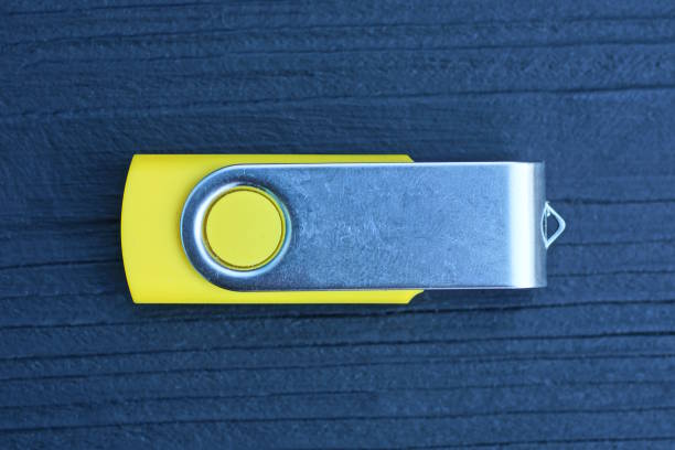one small gray yellow closed mobile flash drive lies on a black wooden table