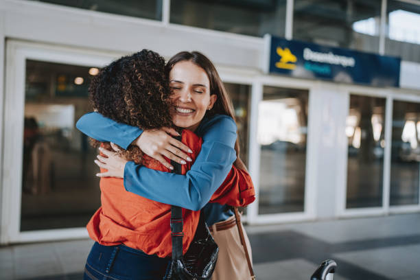 due amici che si incontrano all'aeroporto - abbracciare una persona foto e immagini stock