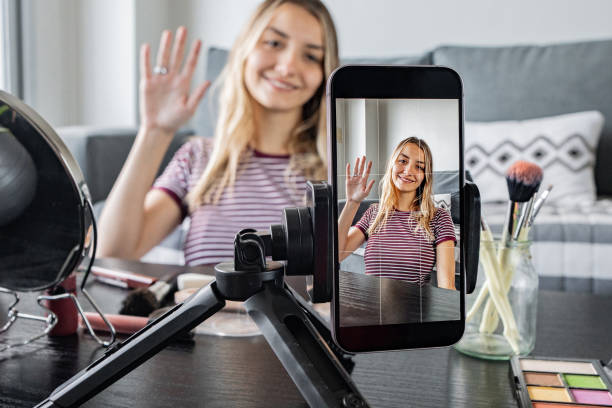 istock Mobile phone filming a woman vlogging makeup tutorial at home 2162155885