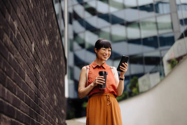 istock Asian woman drinking coffee and using phone after work 2162157562