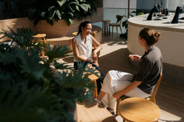 istock Two friends sitting at modern cafe and talking 2162163514