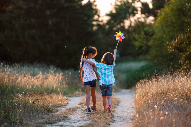 istock Children on path with pinwheel, arms around each other 2162166256