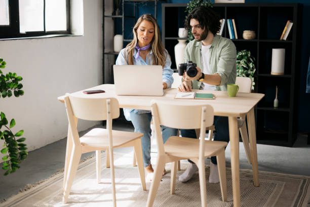 istock Two graphic designers discussing over photographs on digital camera at desk 2162166796
