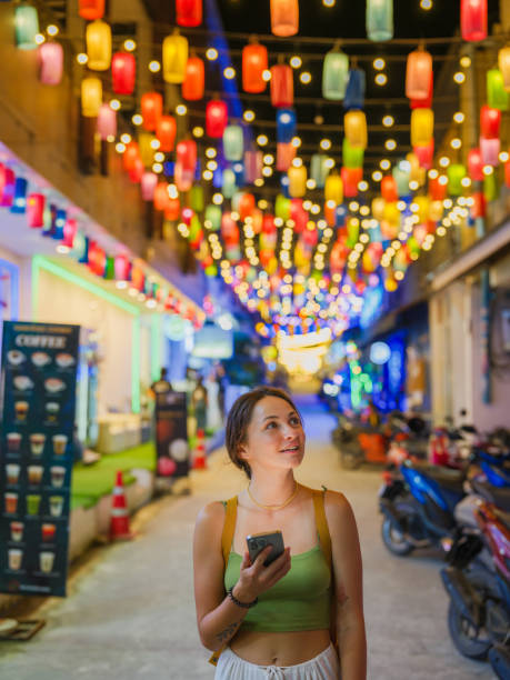 istock Woman using smartphone walking on street illuminated by lanterns on Ko Phangan at night 2162168151