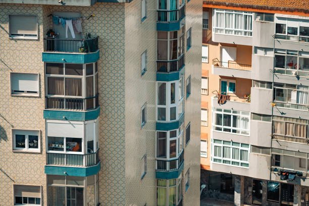 Detailed view of apartment buildings in Lisbon, featuring intricate tiled facades and balconies. The image captures the urban architecture, with laundry hanging from one balcony, daily city life