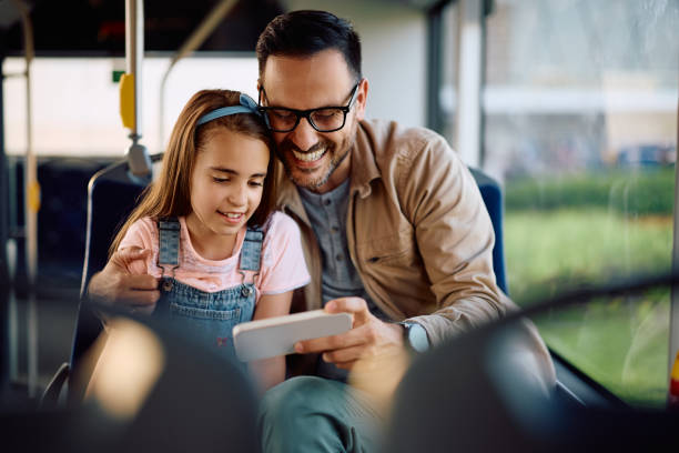 istock Happy man and his daughter using cell phone while commuting by bus. 2162177183