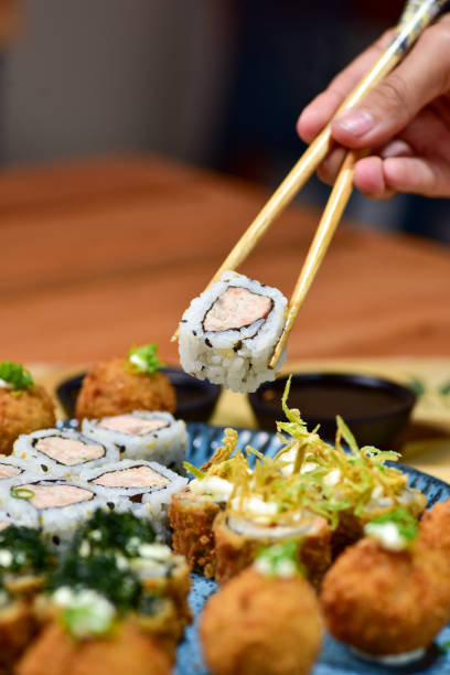istock Female hand serving with chopsticks Baked maki sushi. 2162177492