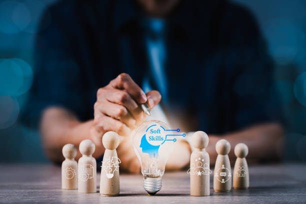 istock A man is pointing at a light bulb on a table with wooden figurines 2162183658