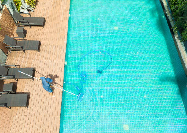 istock Pool maintenance with scoop net  and automatic robot cleaner. 2162184634