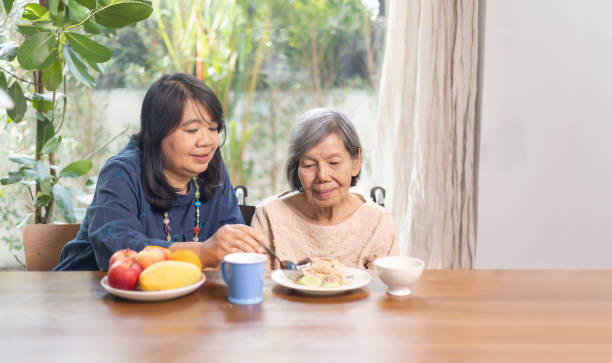 istock Daughter feeding elderly mother with  
Chicken Rice in lunch. 2162184691