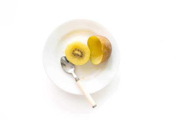 Cut gold kiwi slices and spoons in a white dish