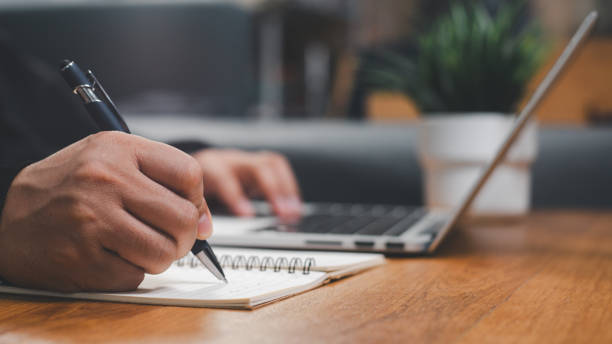 istock businessman working at work table,home office desk background, checklist writing planning investigate enthusiastic concept. Male hand taking notes on the notepad. 2162194809
