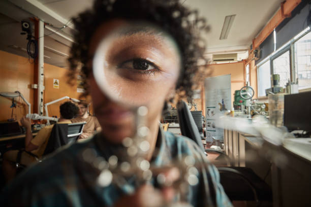 Close up of African American male scientist using magnifying glass in laboratory and looking at camera.