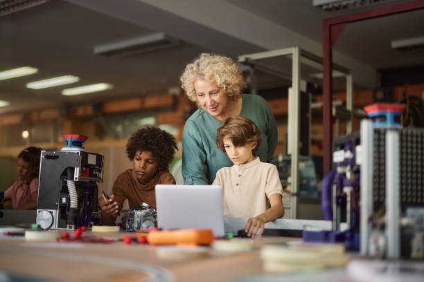 istock Female teacher and schoolboys using laptop in laboratory. 2162200854