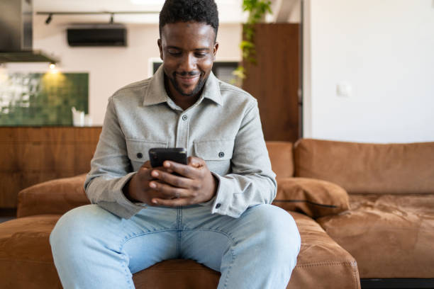 istock Young man surfing the net while sitting on sofa  in living room at home 2162201736