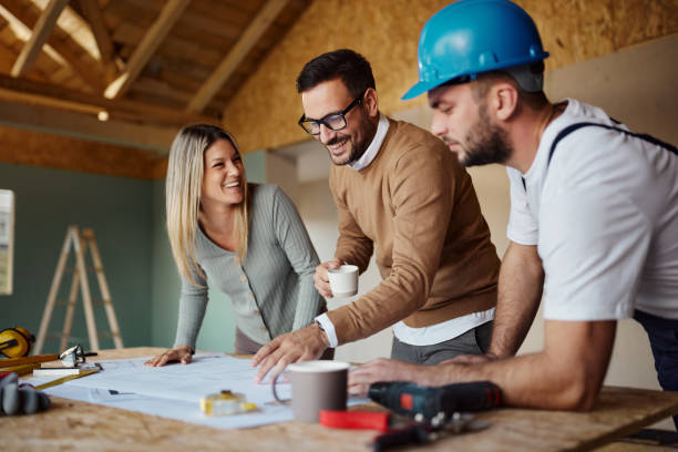 istock Happy couple and manual worker working on plans at construction site. 2162202377